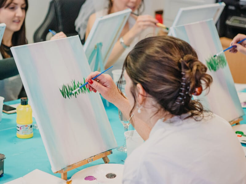 A woman paints a canvas with watercolours